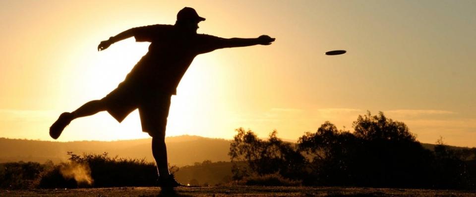 Man throwing a disc at sunset