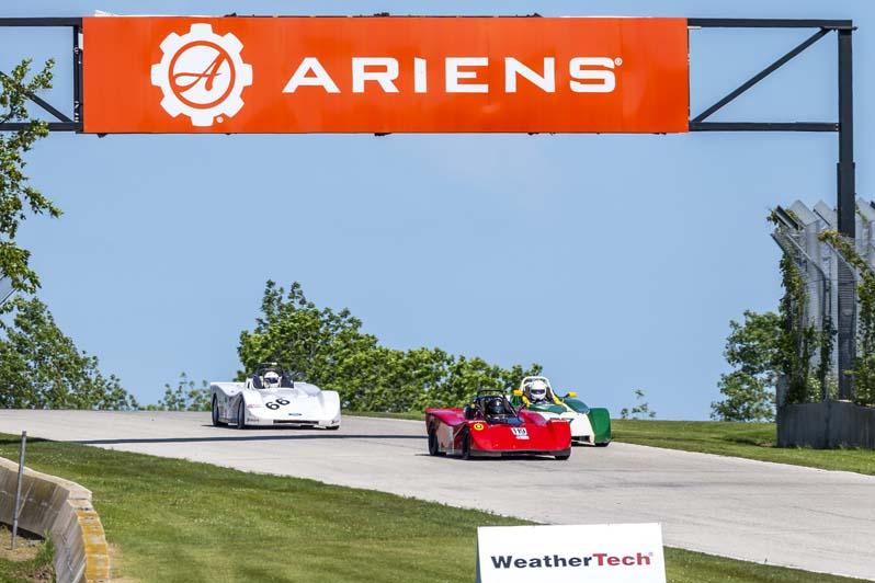 2 stock race cars on the track with Chevrolet and Briggs & Stratton advertisements in background
